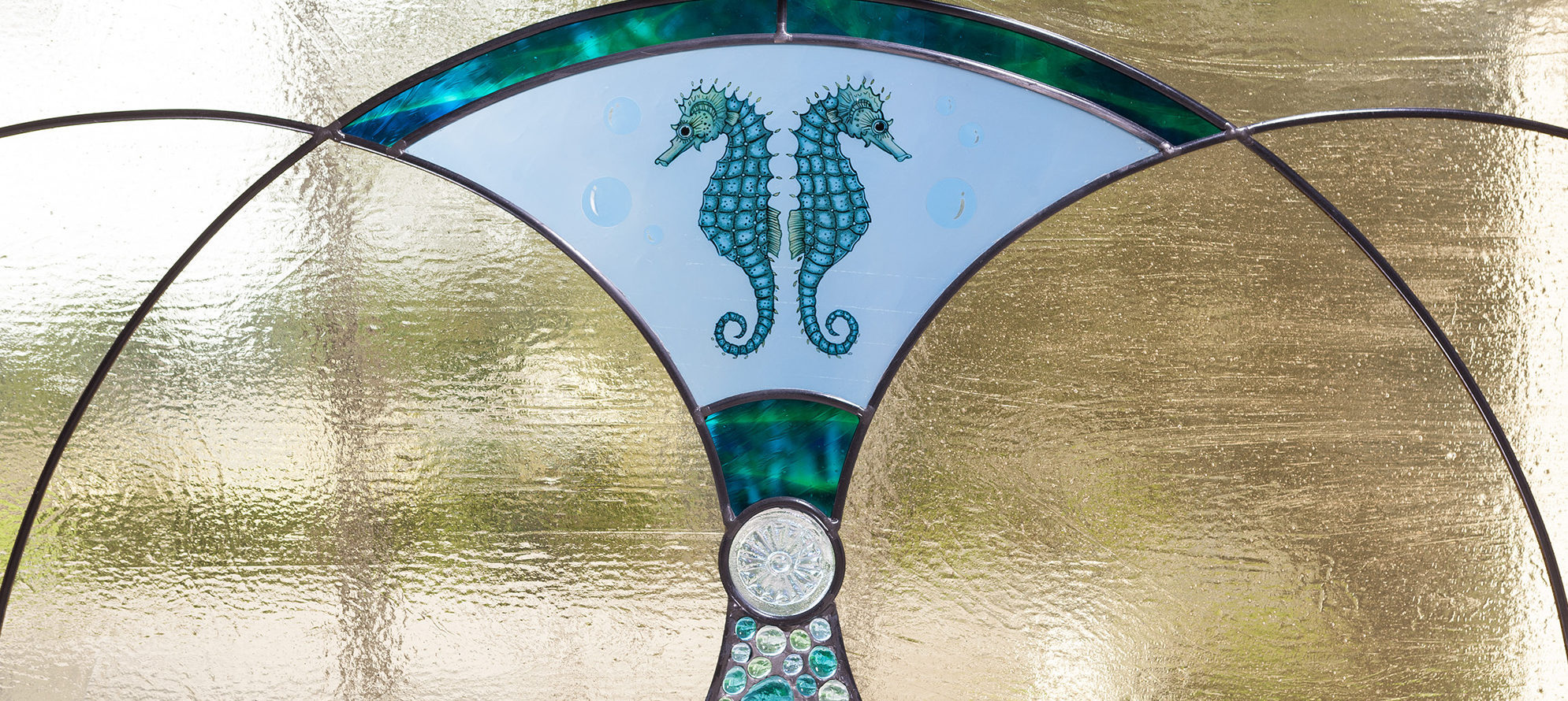 Detail photo of art glass entryway with 2 hand-painted sea horses and Tiffany casted jewel