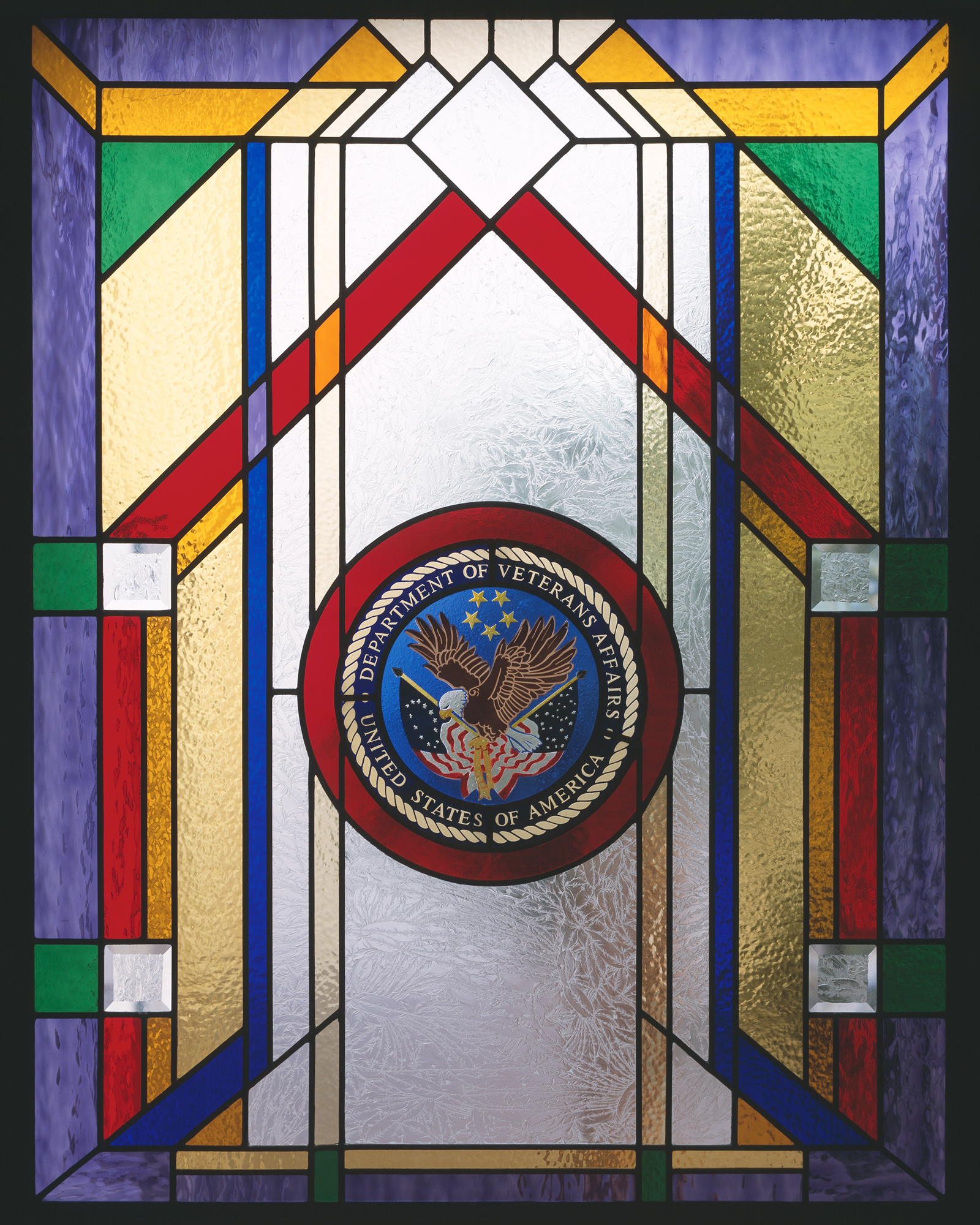 stained glass window with purple, red, green, amber and clear glass with veteran emblem in center