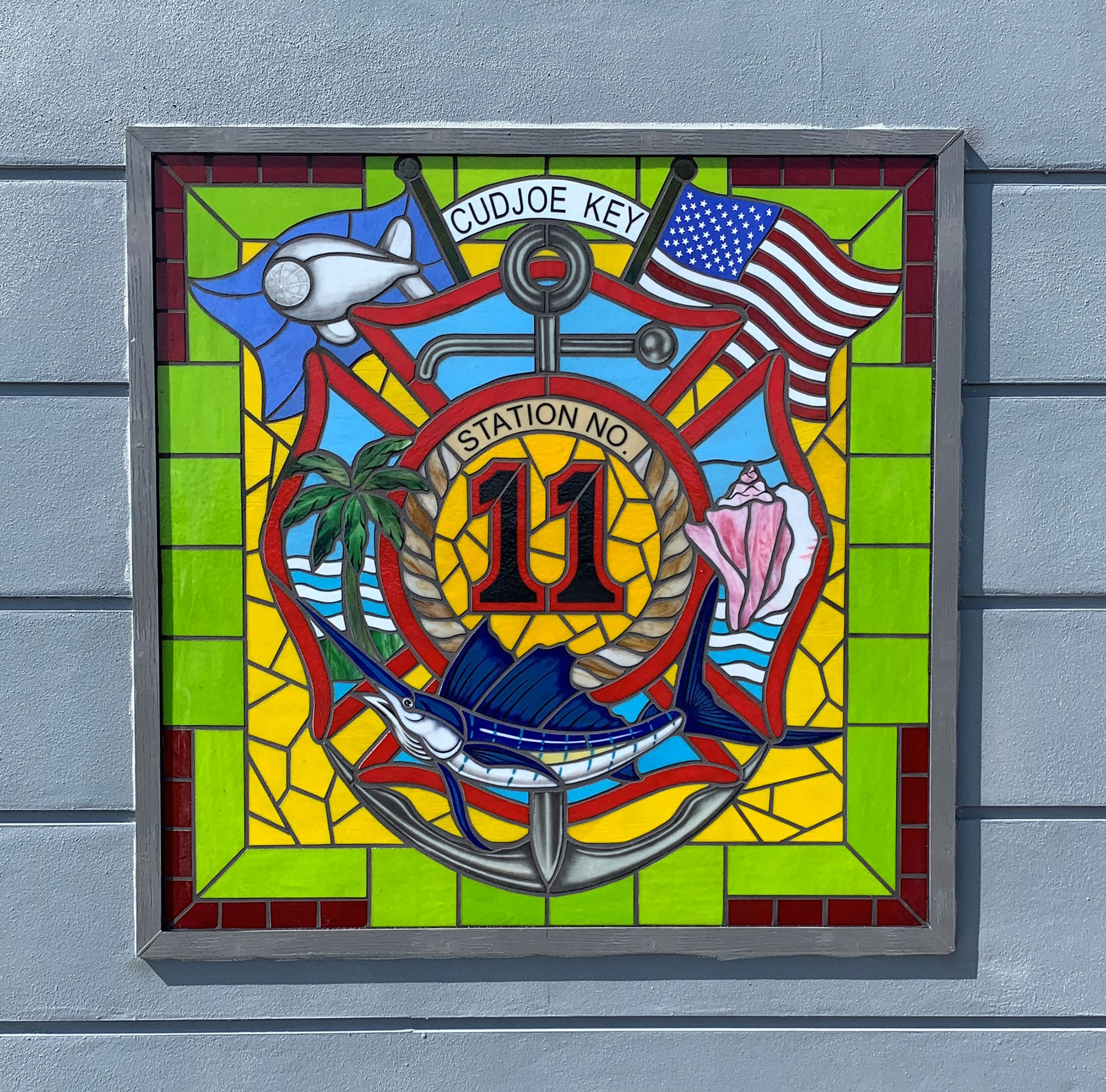 Traditional style stained glass window with red, green, and yellow colored glass and the fire station number.