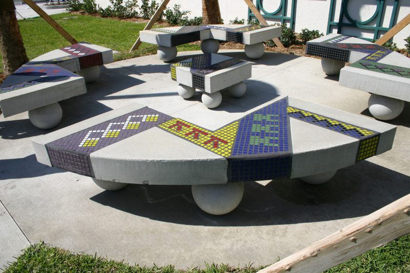 Public art mosaics in park benches in a traditional style with blue and green colored glass.