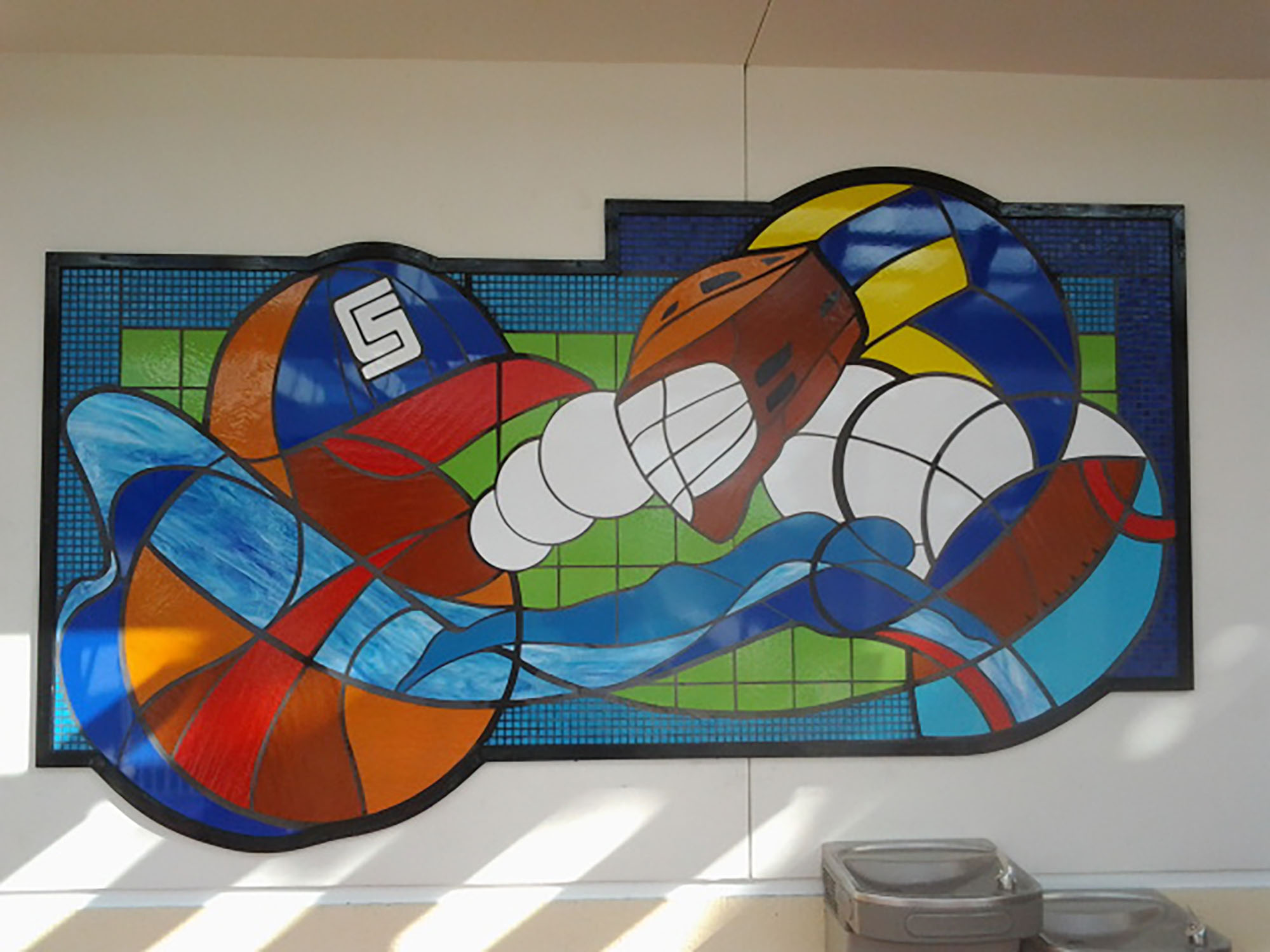 Contemporary style stained glass window of different sport balls in various colorful pieces of glass.