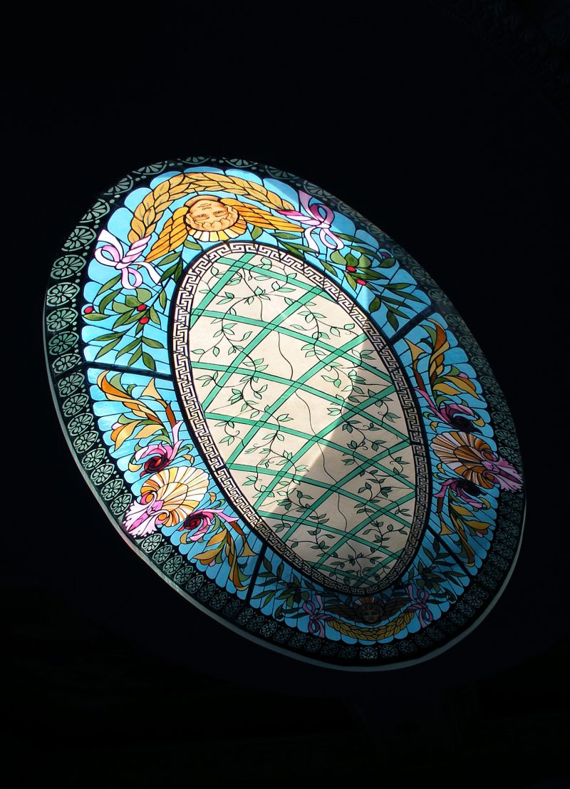 oval ceiling dome with blue and beige colored glass. amber cherub angels on each side of oval with colored foliage design