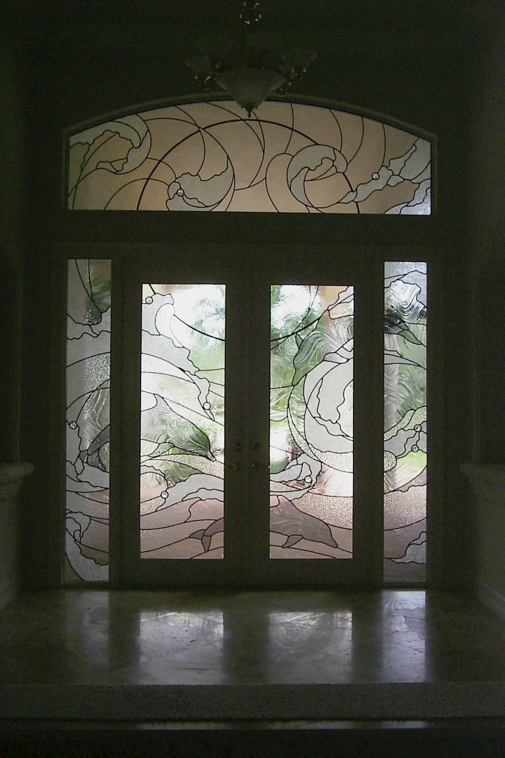 Modern an contemporary style entryway of ocean waves and dolphins with clear and clear textured glass.
