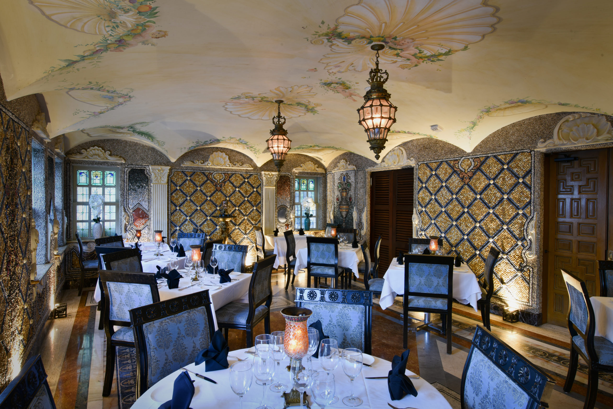 traditional fine dining space with mosaic tile work on walls and stained glass windows in the distance