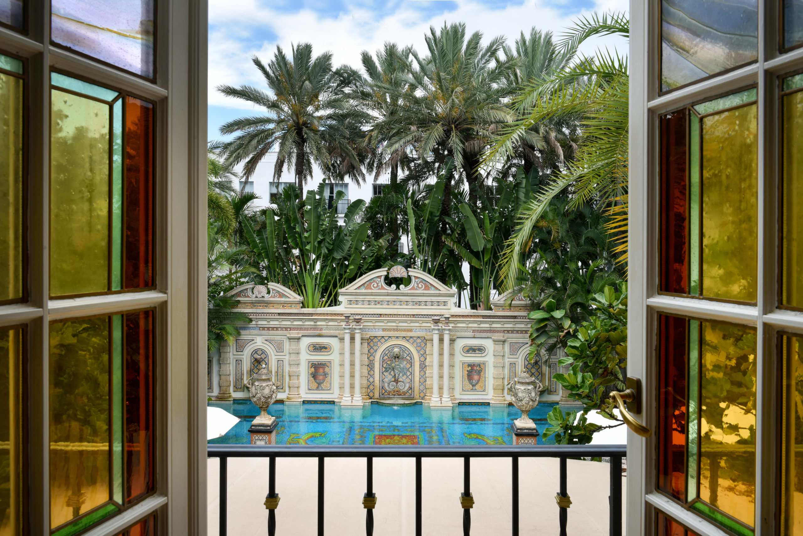 looking out of window with yellow and red stained glass. looking onto a pool with decorative tile work