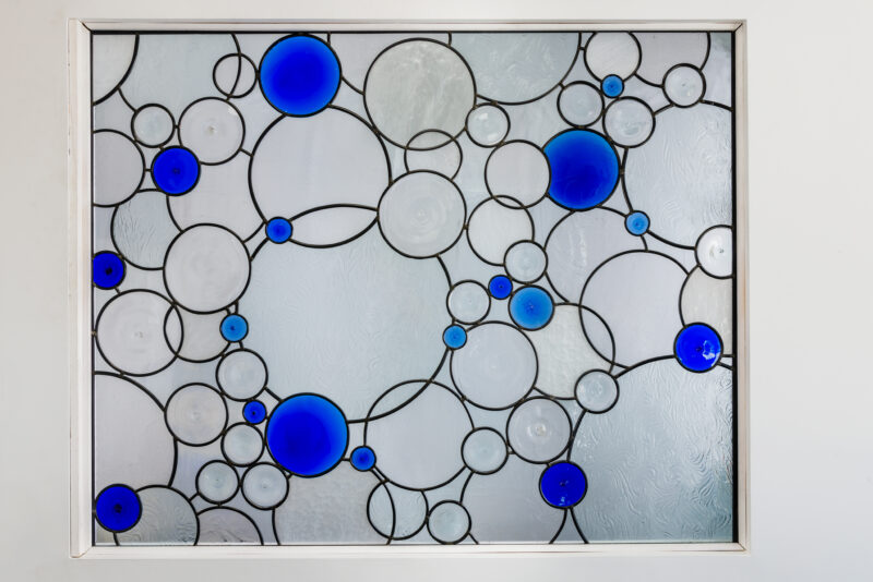 stained glass window with bubble design. clear and cobalt blue textured glass, rondels, bottle bottoms.